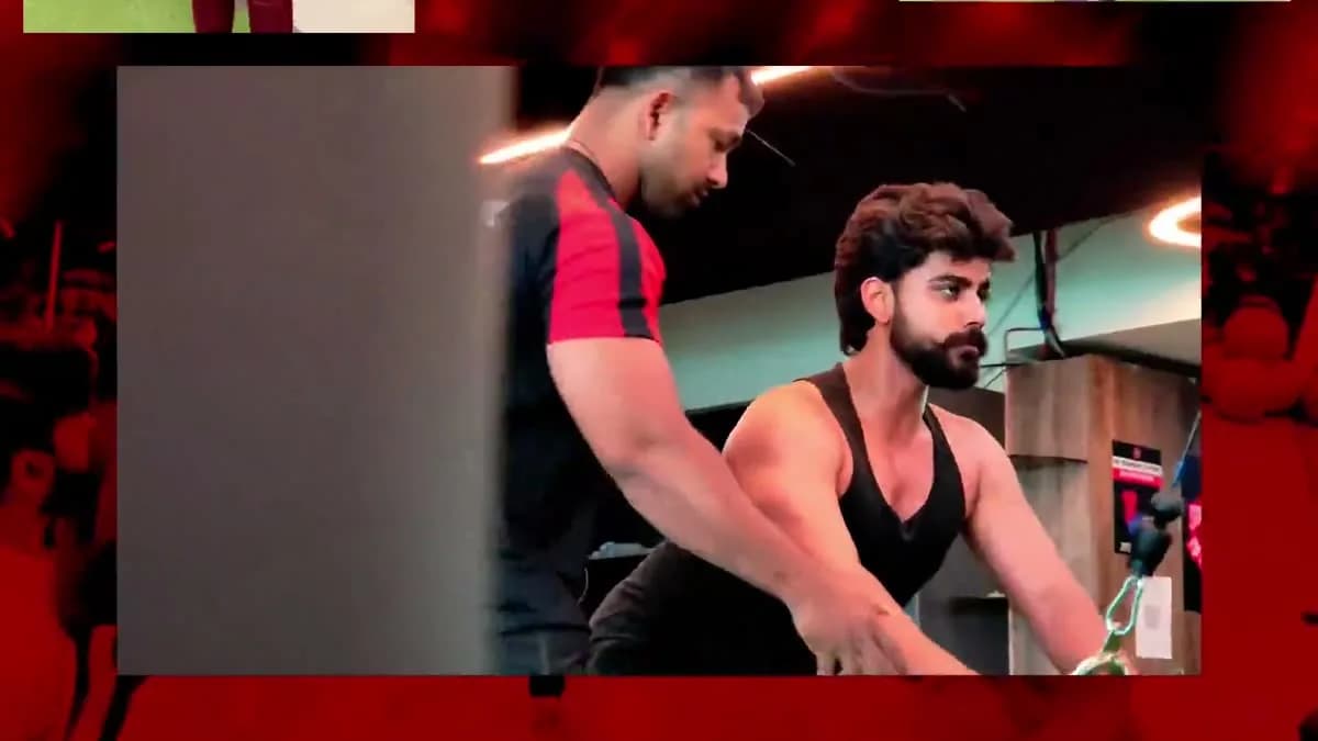 A WTF trainer guiding a member through a cable-machine exercise on the gym floor